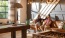 a couple of women sitting on a couch in a room with chandeliers and a table