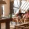 a couple of women sitting on a couch in a room with chandeliers and a table