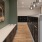 a room with a wood floor and a white counter with a black and white wall with art on